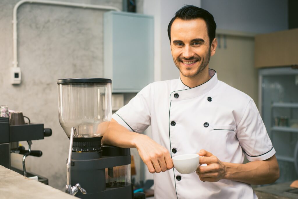 Hombre con uniforme de chef en una cocina moderna, trabajando con Akre Cocinas, Cocinas Málaga y armarios de cocina.